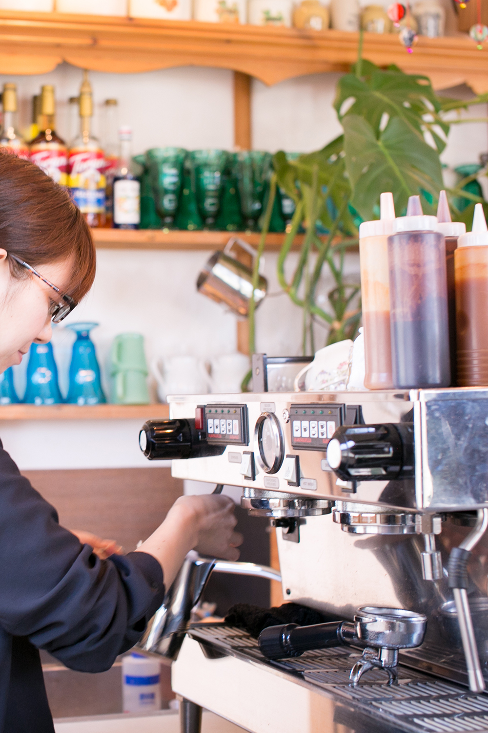 カウンターの中でエスプレッソマシン La Marzocco を操作するスタッフと、棚に並ぶグラスやボトル(アンティーク&オールディーズ公式サイトより)