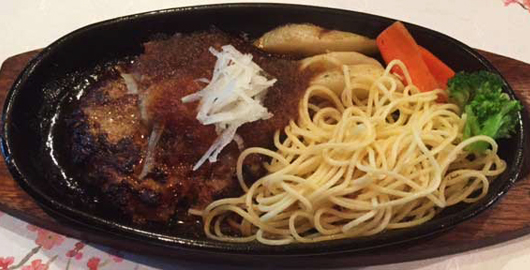 鉄板の上で、白髪ねぎがのった和風ソースのハンバーグとパスタ、野菜の付け合わせ(カフェリーフ公式サイトより)