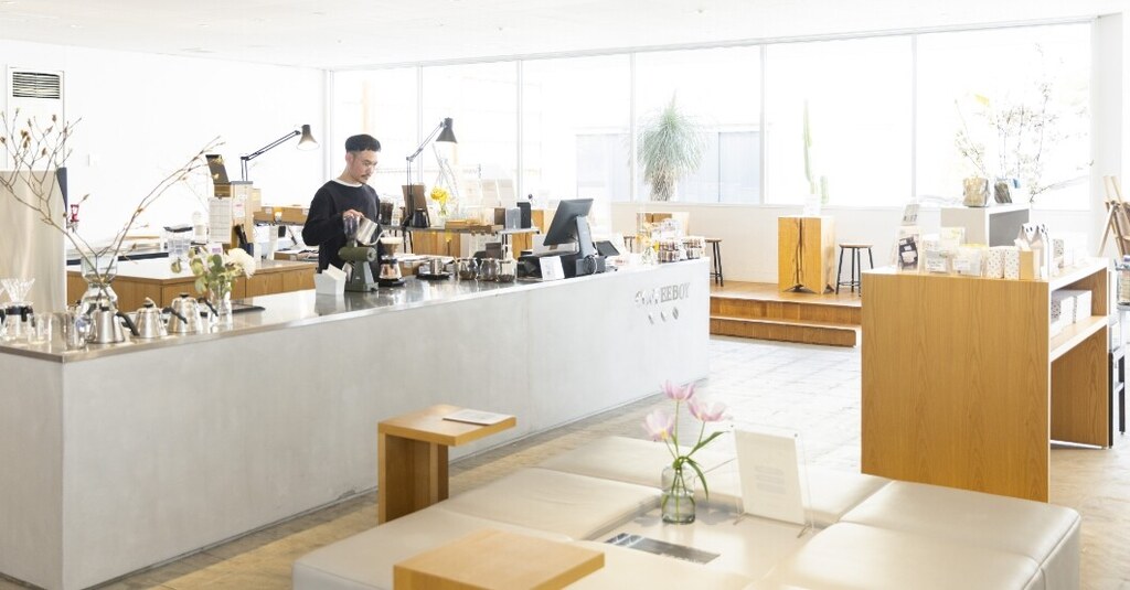 COFFEEBOY新下関店の明るい店内、カウンターで淹れるスタッフと窓辺のソファ席(公式サイトより)