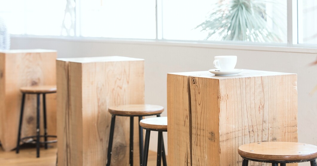 COFFEEBOY新下関店の木製スツールとテーブル、コーヒーカップ(公式サイトより)