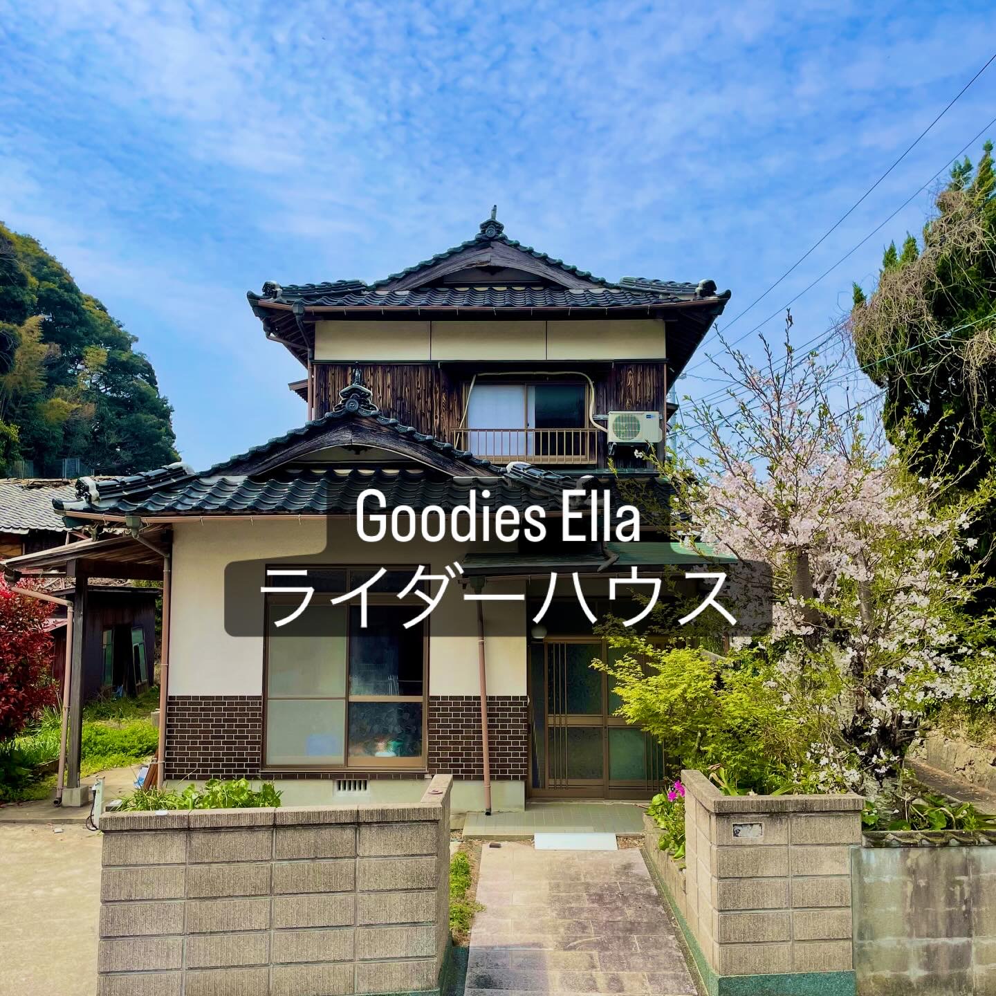 「Goodies Ella ライダーハウス」の文字が入った、瓦屋根の2階建ての古民家。庭には花の咲く木がある（Goodies Ella公式Instagramより）