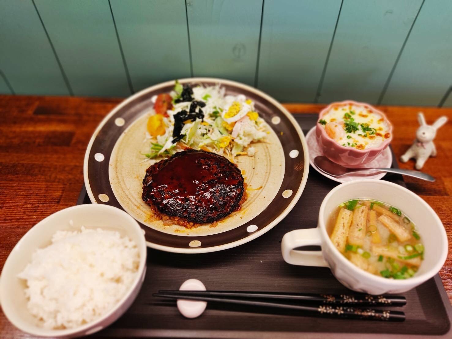 花cafeの日替わりランチ例。照り照りの煮込みハンバーグにサラダ、茶碗蒸し風の小鉢、根菜のスープが添えられたワンプレート(花cafe公式サイトより)