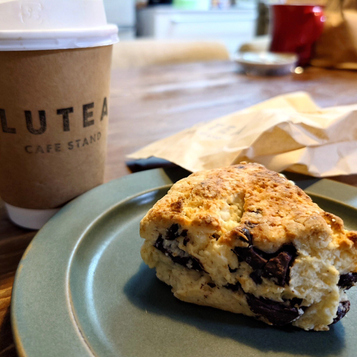 LUTEA CAFE STANDのロゴ入りコーヒーカップと、チョコレートがごろごろ入った手作りスコーン(LUTEA CAFE STAND公式Instagramより)