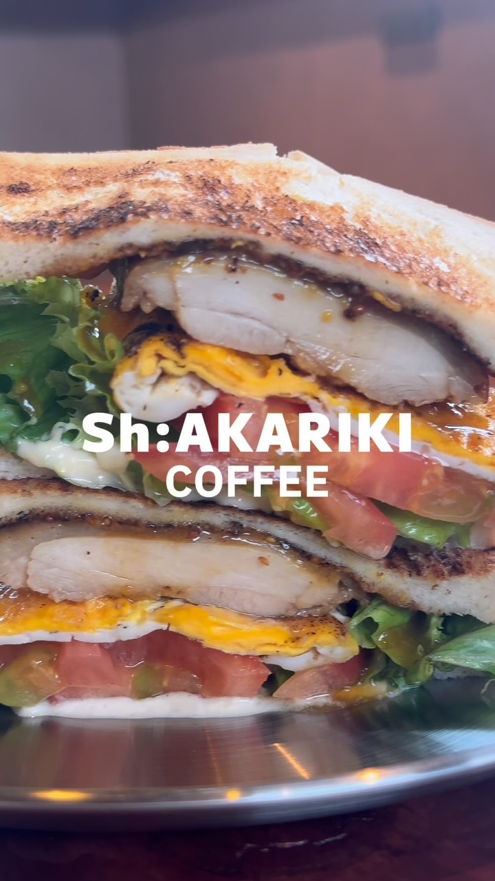こんがり焼いたパンに、チキン、卵、トマト、レタスをたっぷりはさんだ断面のサンドウィッチ(Sh:AKARIKI COFFEE公式Instagramより)