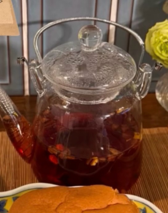 水穀茶房の補血茶。赤みがかったお茶の入ったガラスのティーポットと、手前に焼き菓子の器（公式Instagramより）