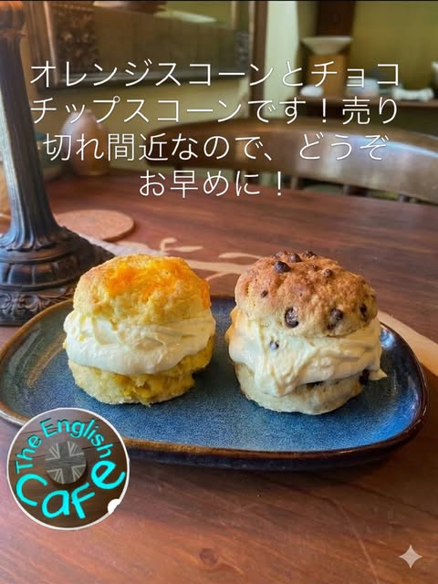 紺色の陶器の皿にのった2つのスコーン。左はオレンジスコーン、右はチョコチップスコーンで、どちらも横に割ってたっぷりのクリームをはさんでいる（The English Cafe公式Instagramより）