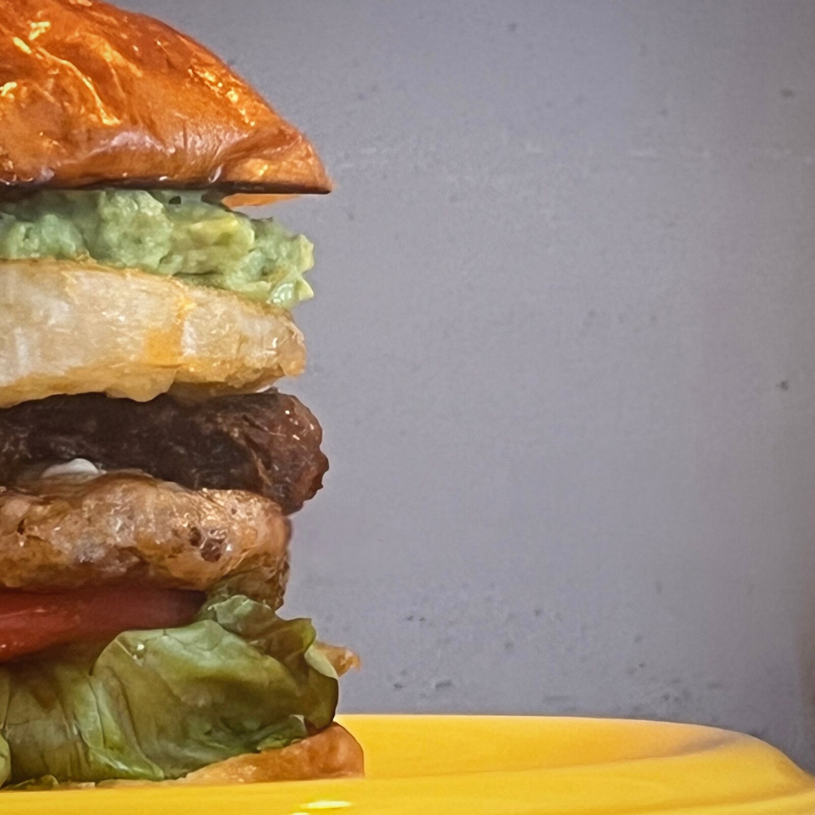 角島OZ BURGERの関門ポークパティバーガーの断面、レタスやアボカド、パティが層になった写真(公式Instagramより)
