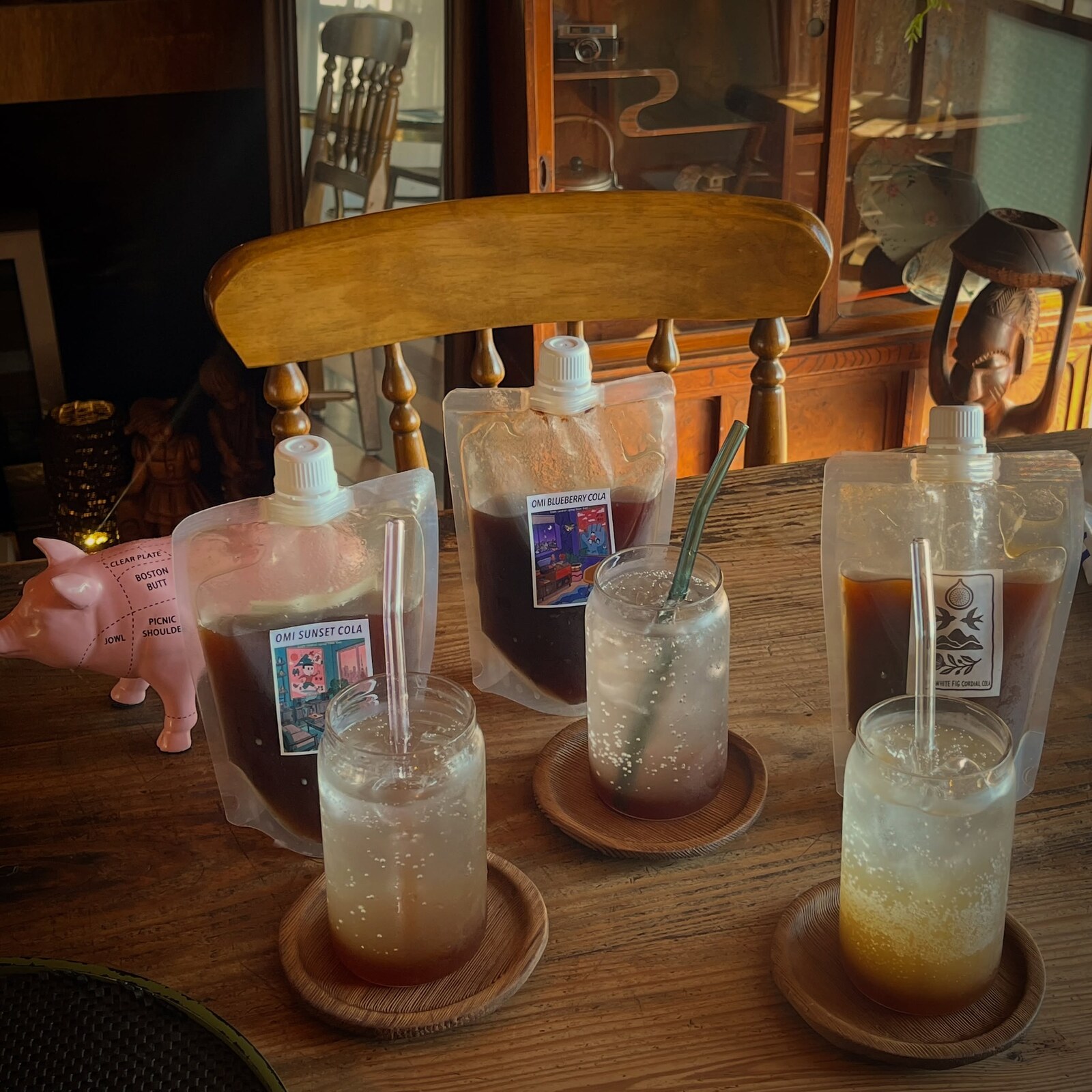 角島OZ BURGER店内でクラフトコーラのパウチとグラスが木のテーブルに並ぶ写真(公式Instagramより)