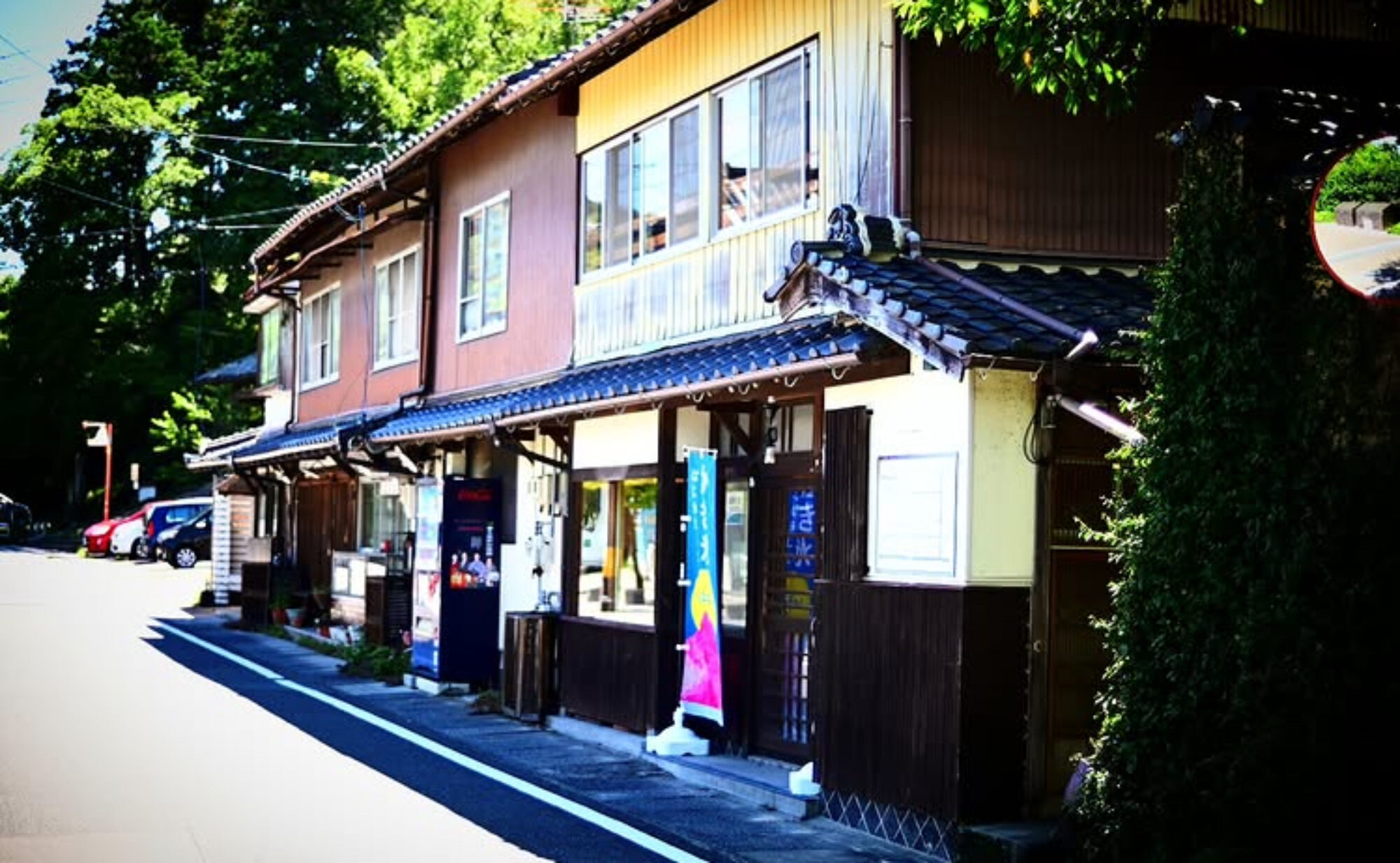 下関市長府川端の古い町並み。瓦屋根と板壁の二階建てが連なり、手前の店先に「かき氷」ののぼりが立つYolo's cafeの外観(合同会社YoloSK公式サイトより)