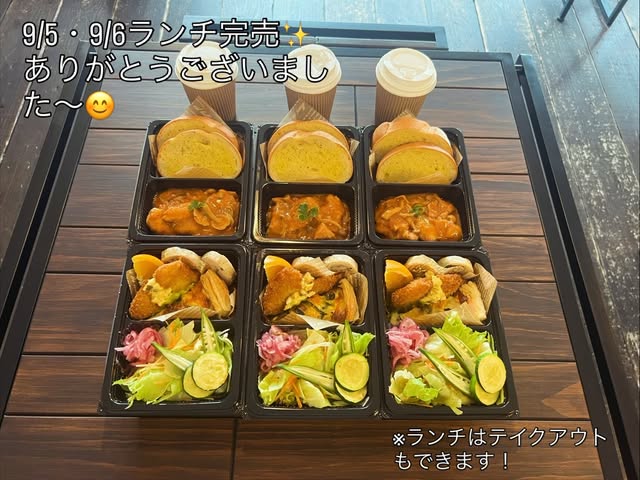 テイクアウト用に詰められたランチ3人分。ガーリックトースト、トマト煮込み、フライとタルタル、サラダとピクルスがそれぞれ容器に分けられ、テイクアウトカップのドリンクが添えられている(Yolo's cafe公式Instagramより)