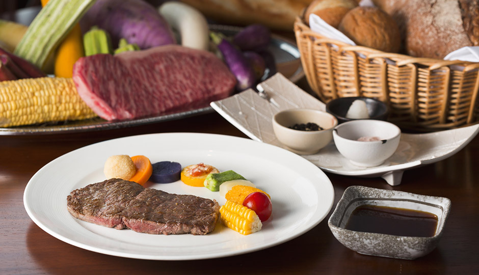 日和庵のステーキ料理。彩り野菜とパンかごが添えられたメインディッシュ(公式サイトより)