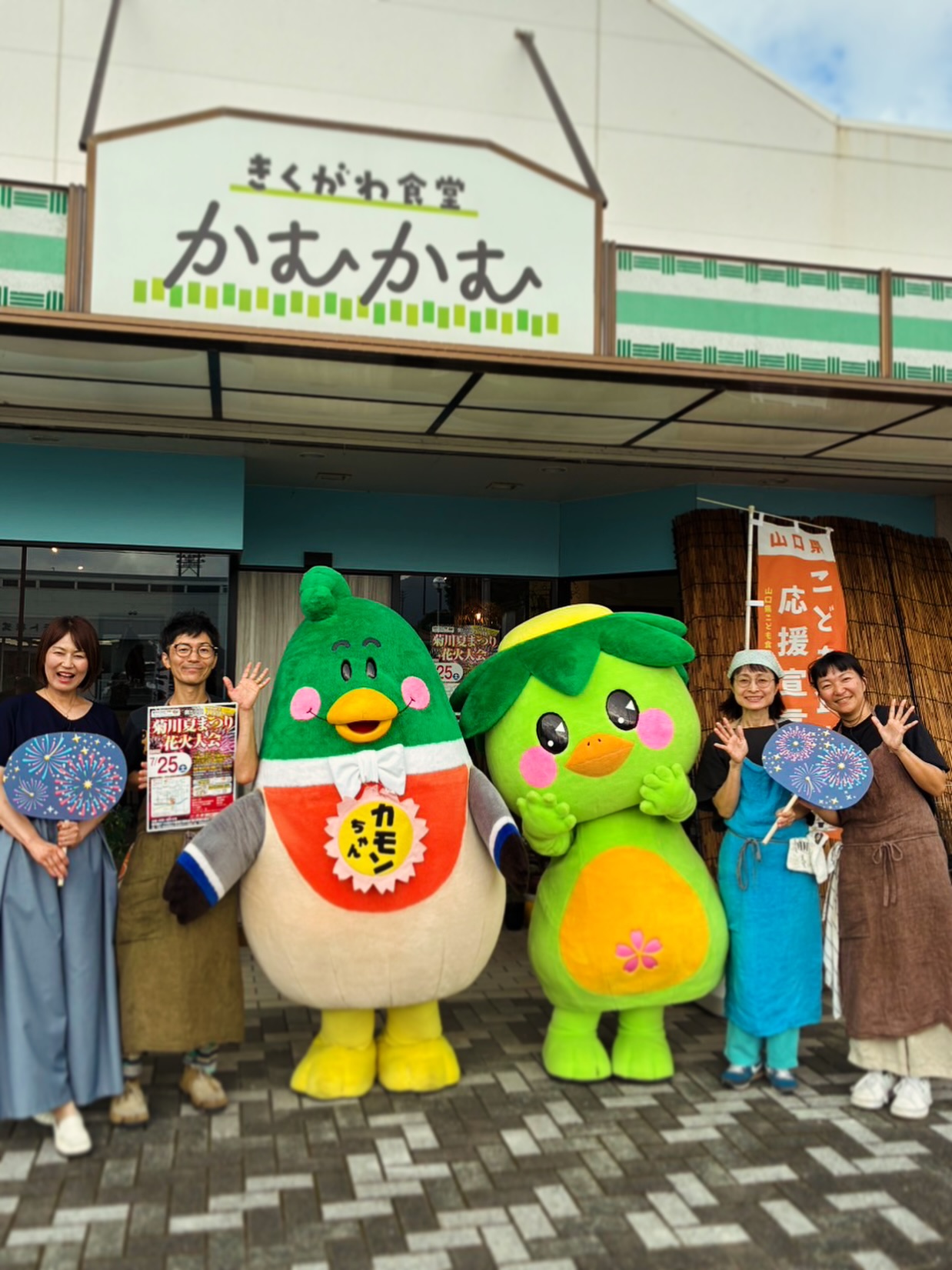 きくがわ食堂かむかむの外観と、ご当地キャラクターと一緒に写るスタッフ(公式Instagramより)