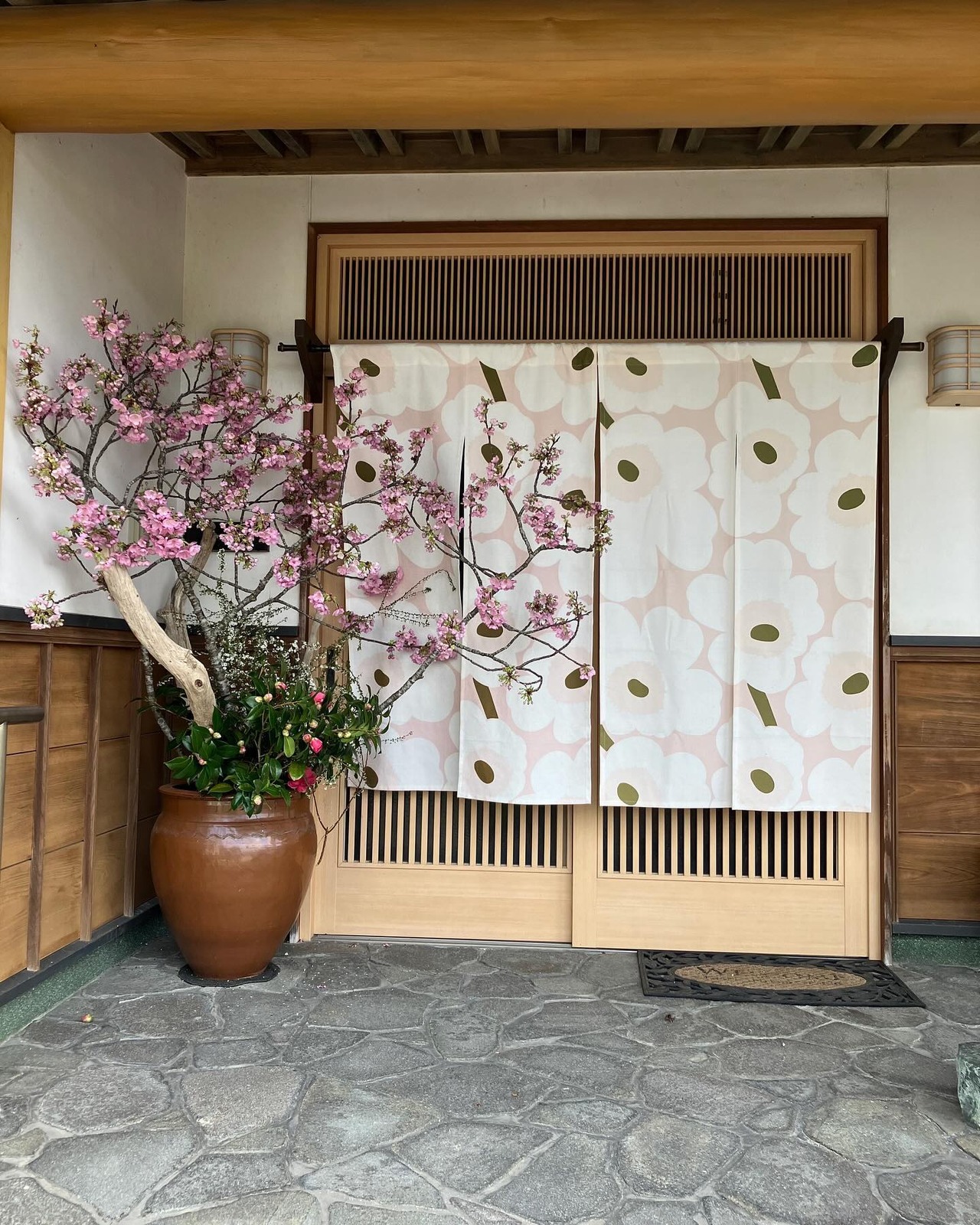 さくらカフェの入口ののれんと桜の枝（公式Instagramより）