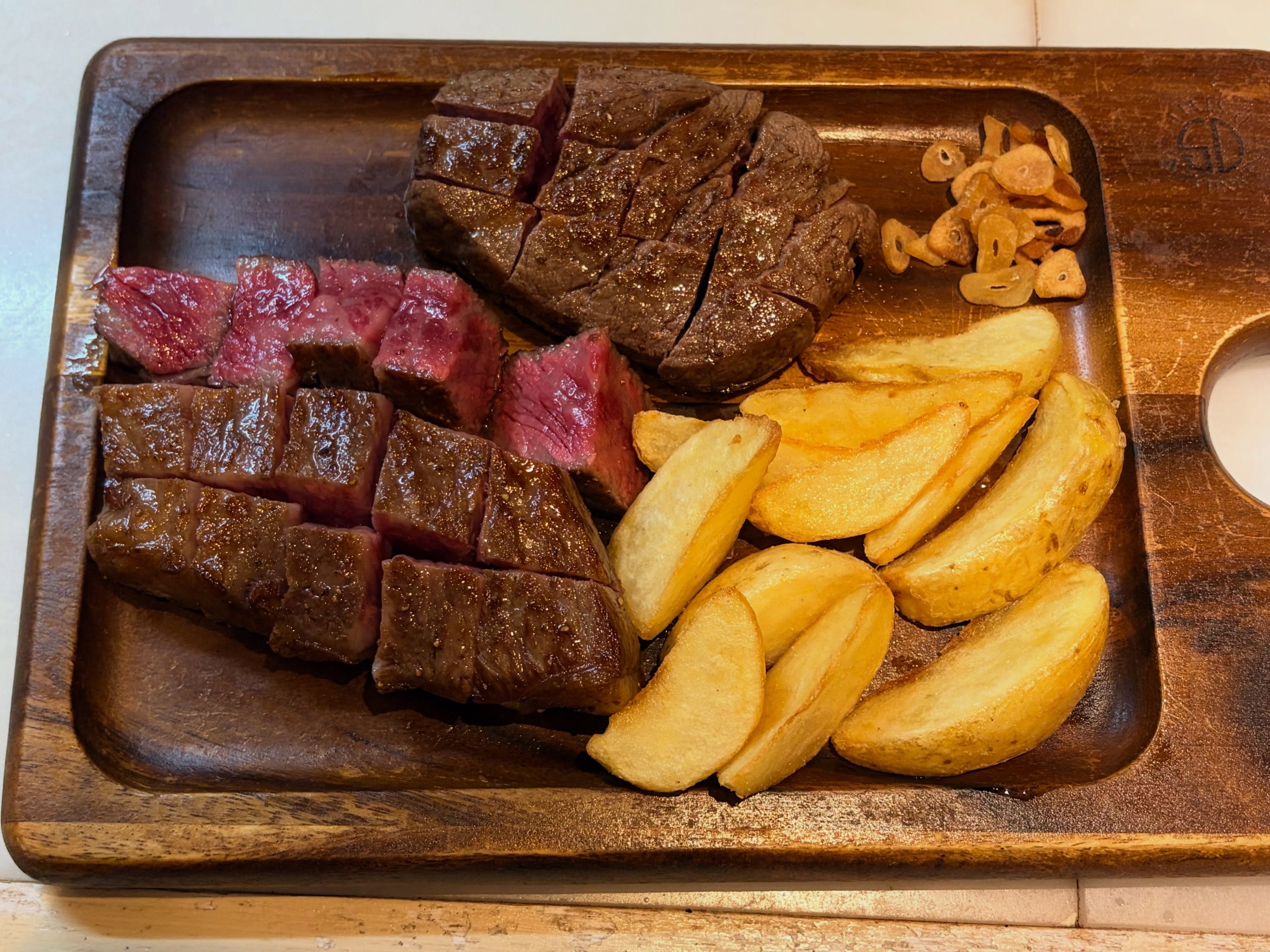 鉄板 笑和の鉄板焼きステーキ。ロゼ色に焼き上がったお肉とポテトウェッジ、ガーリックチップ(公式Instagramより)