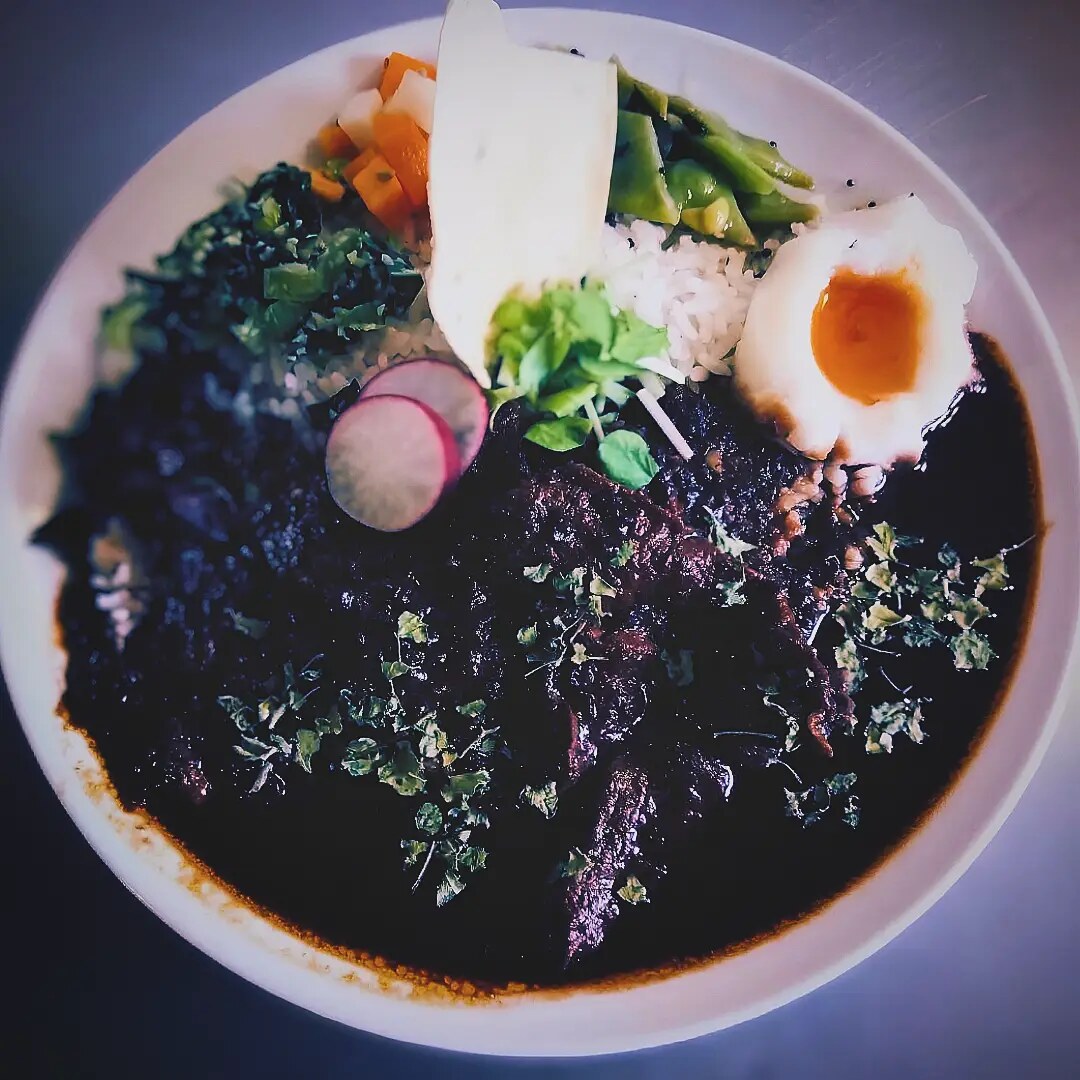 咖喱家ゆるりの黒いスパイスカレーと半熟卵、彩り野菜のプレート(公式Instagramより)